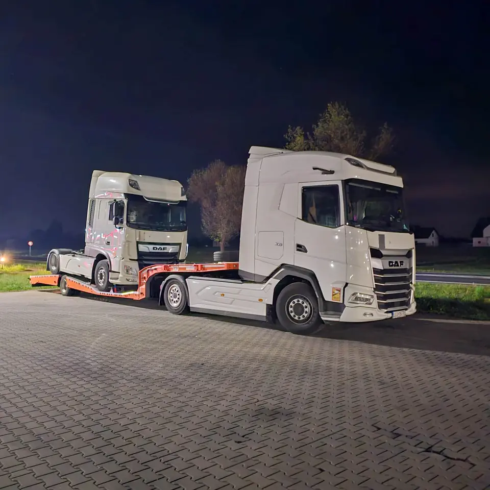 Ciągnik siodłowy przewożony na naczepie niskopodłogowej nocą